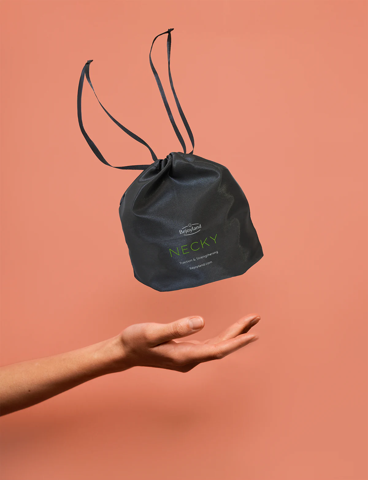 A small drawstring bag with the portable neck trainer labeled Bejoyland NECKY levitates above a hand.