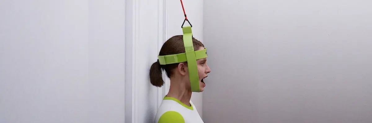 Woman wearing the Bejoyland NECKY chin strap performing a jaw-opening platysma exercise against elastic resistance